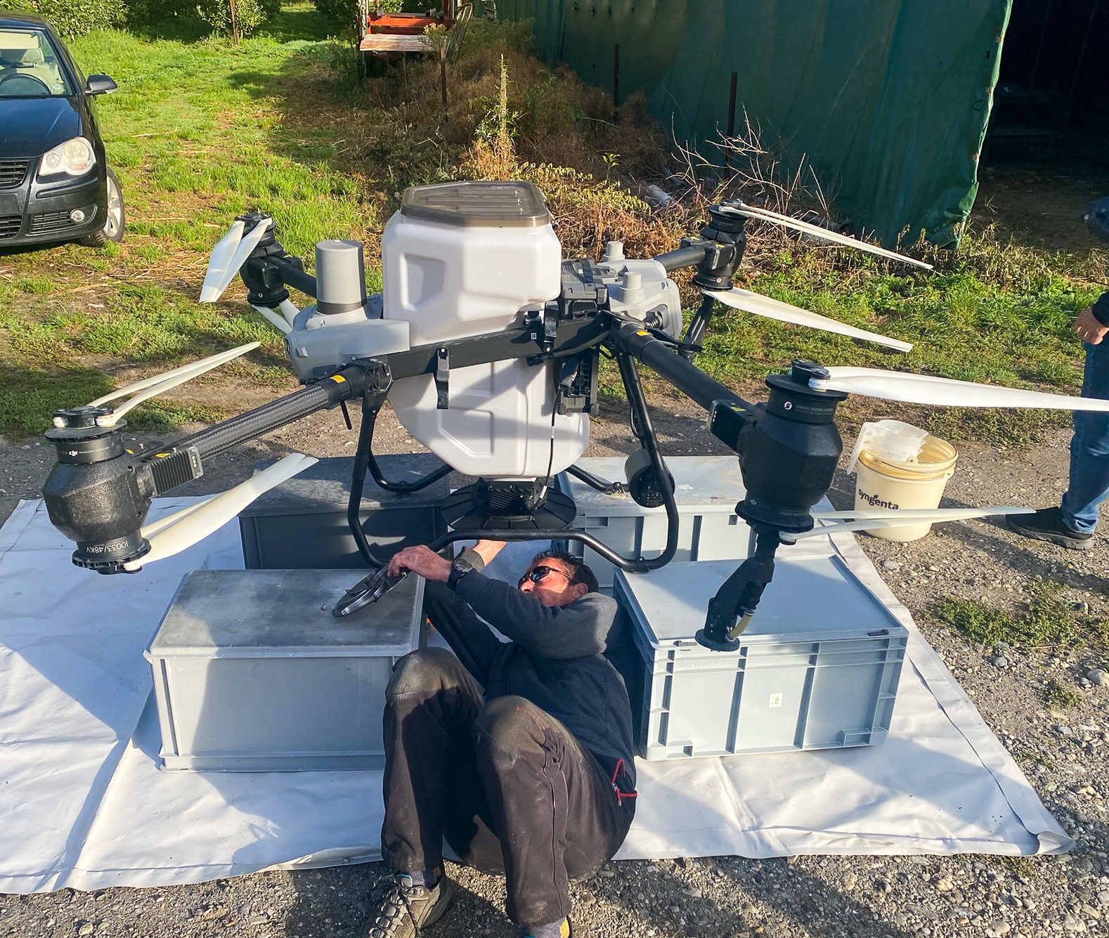 Technicien effectuant la maintenance d'un drone DJI Agras T50 sur le terrain.