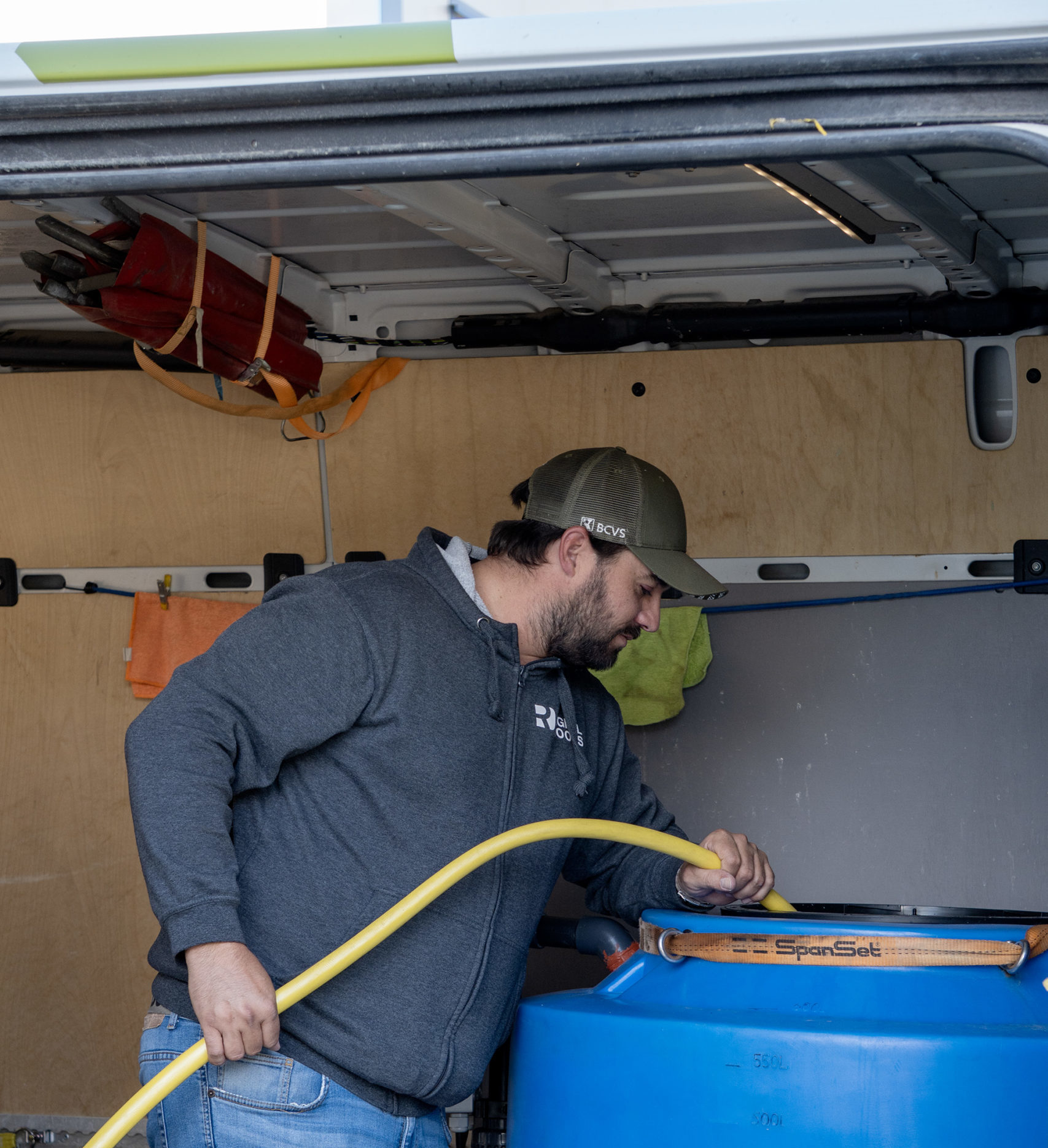 Employee filling a blue tank with a yellow pipe inside a Digital Roots technical van.