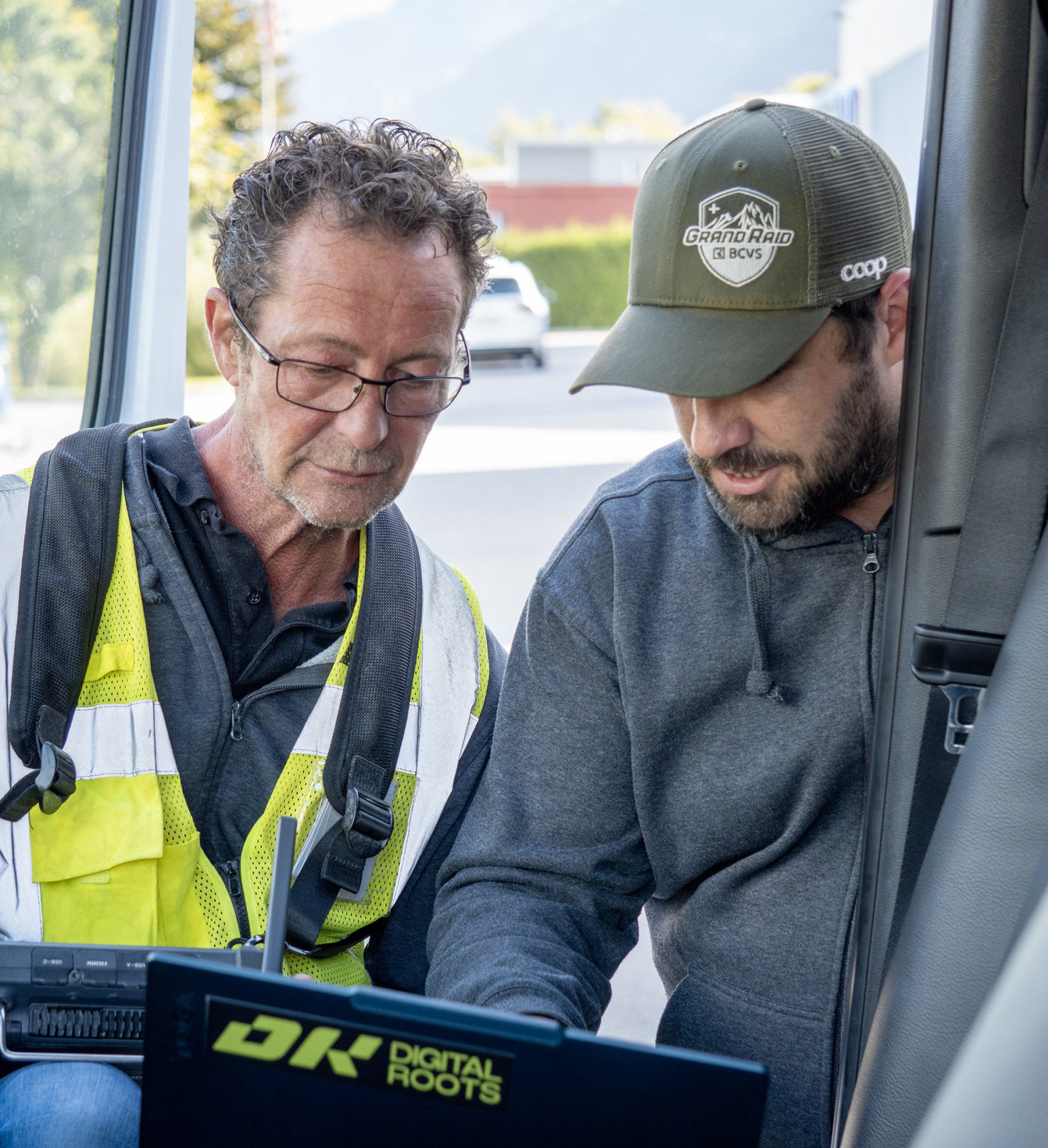 Deux employés Digital Roots analysent des données sur un PC portable à l’intérieur d’un véhicule, lors d’une intervention.